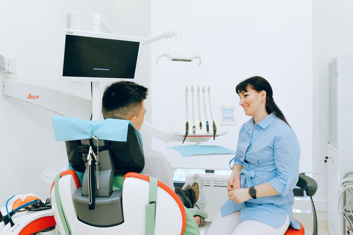 Dentista conversando con un paciente en el consultorio.